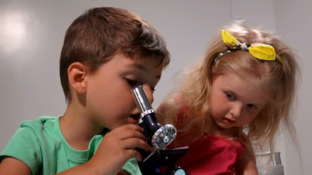 Uroczy chłopiec i dziewczynka są zdumieni obrazem w soczewce mikroskopu — Wideo stockowe
