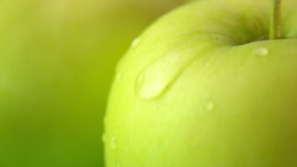 Super close-up of a drop of water flowing down a large ripe juicy green apple — Stock Video