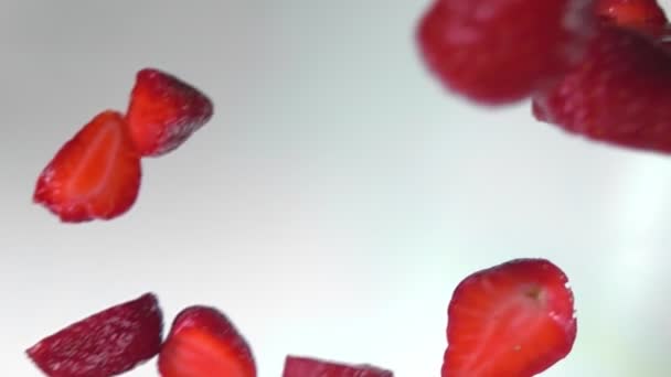 Metades de grandes morangos suculentos estão caindo diagonalmente no fundo branco — Vídeo de Stock