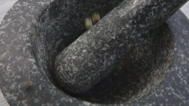 Baharatlı biberler gri taş havan topuna dökülüyor.