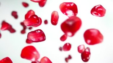 Beyaz arka planda zıplarken sulu nar tanelerinin süper yakın çekimi