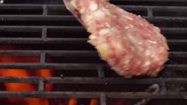 Izgara ızgarasına koyulan ev yapımı hamburgerin en yakın görüntüsü.