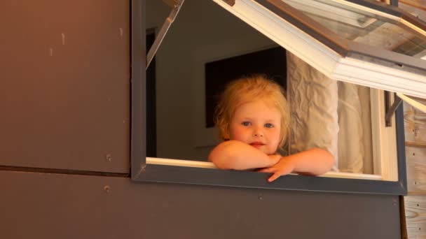 Urocza dziewczynka wygląda przez otwarte okno — Wideo stockowe