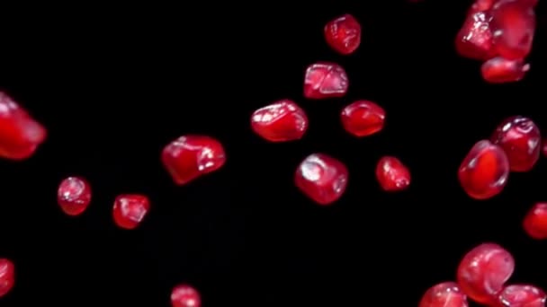 Красные сочные спелые гранатовые зерна падают по диагонали на черном фоне — стоковое видео