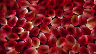 Tatlı su, koyu arkaplandaki kırmızı nar tanelerinde akıyor.