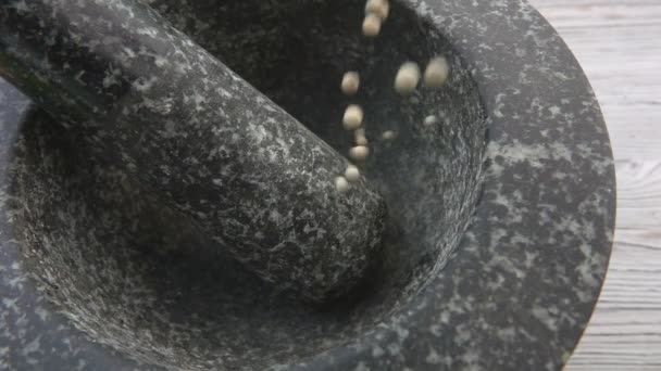 Primo piano dei grani di pepe bianchi che cadono nella malta di pietra grigia — Video Stock