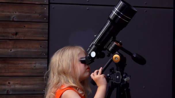 Una niña está explorando el cielo a través de un telescopio — Vídeo de stock