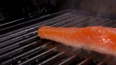 Izgarada çiğ somon bifteği yanıyor. 