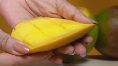 Eller olgun mangoyu açıyor. Mangonun arka planındaki küplere yarıya bölünmüş halde.