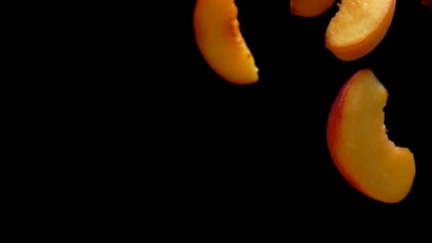 Nahaufnahme von saftigen Hälften reifer Aprikosen, die auf schwarzem Hintergrund fliegen — Stockvideo