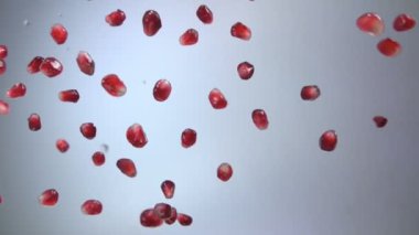 Kırmızı sulu olgun nar taneleri gri arka plana düşüyor.