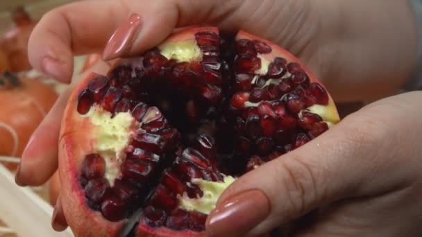 Kvinnliga händer bryter ett rött moget granatäpple i de sex bitarna — Stockvideo