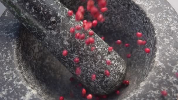 Super close-up de pimenta rosa picante caindo na argamassa de pedra cinza — Vídeo de Stock