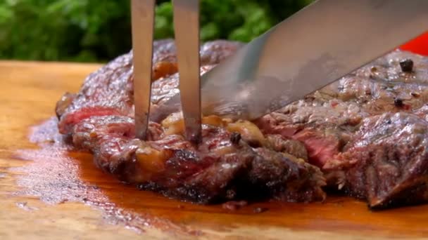 Aşçı, ahşap bir tahtadan lezzetli bifteğin bir parçasını keser ve alır. — Stok video