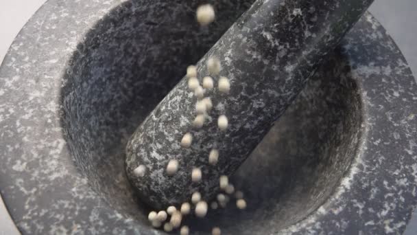 Super close-up dos grãos de pimenta branca caindo na argamassa de pedra cinza — Vídeo de Stock