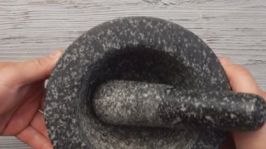 Erkek ellerinin üst görüntüsü gri taş havan topuzunu bir tokmakla yerleştiriyor.