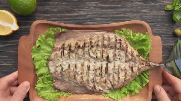 Vue du dessus d'une assiette avec filet de poisson maquereau grillé placé sur la table en bois — Video