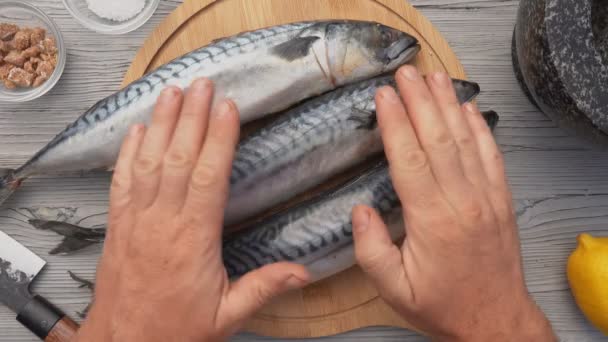 Widok z góry męskich rąk umieszczając okrągłą planszę z trzema rybami makreli — Wideo stockowe