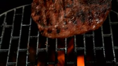 Mutfak maşaları ızgara ızgarasına lezzetli bir biftek koyuyor.