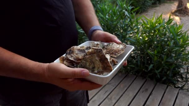 Um homem está segurando um prato branco com ostra deliciosa fresca e escolhendo um — Vídeo de Stock