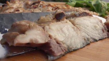 Bir bıçağın yakın çekimi ızgara uskumru balığını ahşap bir tahtadan alıyor.