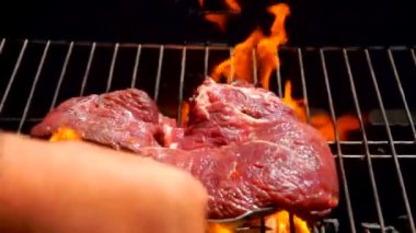 Lezzetli çiğ biftek ızgaranın sıcak yüzeyine düşüyor.