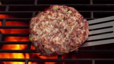 Sulu et burger pirzolasına yakın çekim. Soğanlı ve spatulayla çevrilmiş.