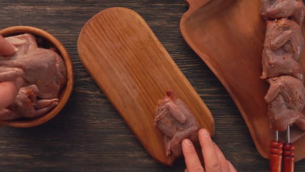 Bovenaanzicht van opperhoofden die ruwe gemarineerde kwartels op het houten bord plaatsen — Stockvideo