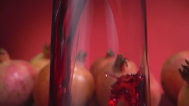Kırmızı arkaplanda bir sürahiye akan nar suyu dalgasının yakın çekimi