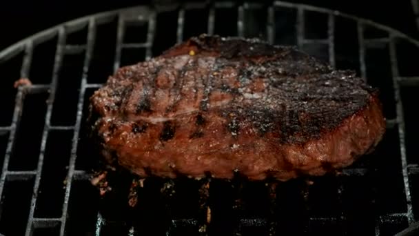 Kitchen tongs are pressing a delicious beef steak to the grill grid — Stock Video