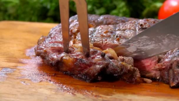 El chef corta y quita un pedazo del jugoso bistec de una tabla de madera — Vídeos de Stock