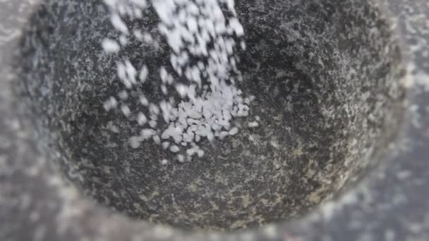 Biała sól morska wpada do zaprawy kamiennej. — Wideo stockowe