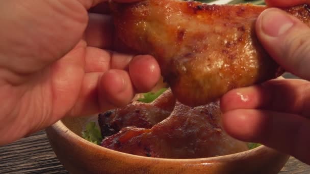 Close-up of a male hand tearing a grilled chicken wing in two parts — Stock Video