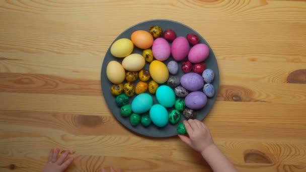Vista superior de las manos de los niños tomando huevos de Pascua de color del plato gris — Vídeos de Stock