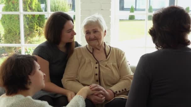 Стара білошкіра жінка сидить зі своєю дочкою та онуками — стокове відео