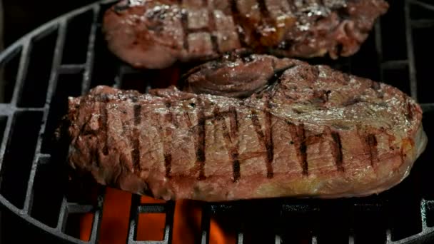 Dva napůl připravené hovězí steaky se smaží na grilu. — Stock video