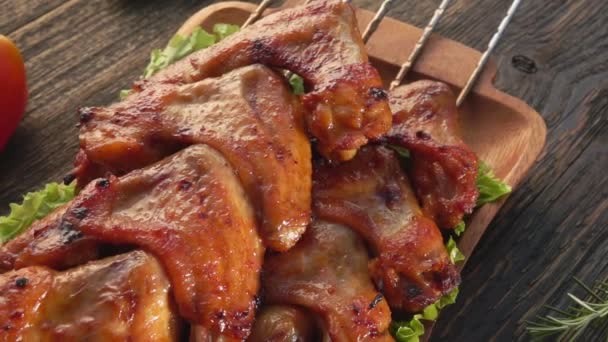 Panorama of fried chicken wings on the skewers on the wooden plate — Stock Video