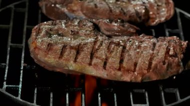 Yangının arka planındaki ızgarada yarı pişmiş biftekler kızarıyor.