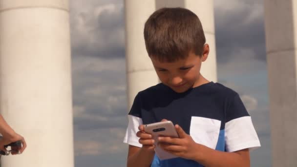 Rapaz sério está olhando na tela do telefone ao ar livre — Vídeo de Stock