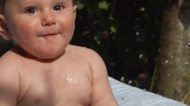 Neşeli kıvırcık çocuk arka bahçede şişme havuzda banyo yapıyor.