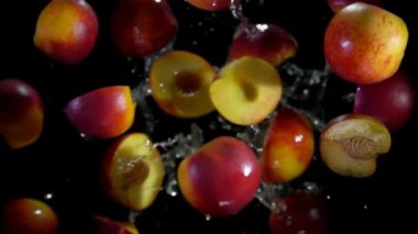 Olgun şeftalinin yarıları su damlalarında uçuyor ve dönüyorlar.