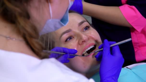 De tandarts in blauwe handschoenen maakt een tandheelkundige reiniging in de mond van een patiënt — Stockvideo
