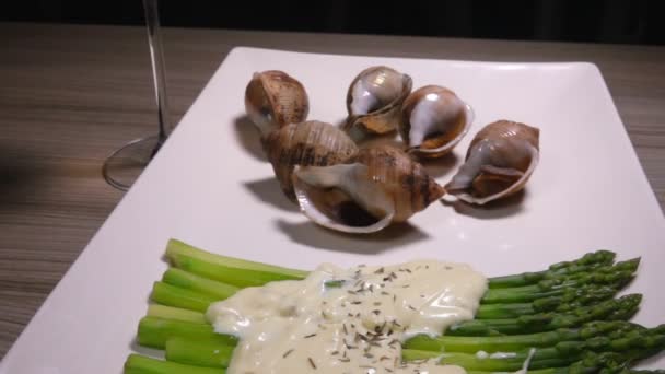 Délicieux escargots de mer cuits avec un plat d'accompagnement d'asperges vertes bouillies — Video