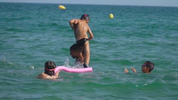 Jovem pai está ajudando o menino a mergulhar na água do mar — Vídeo de Stock