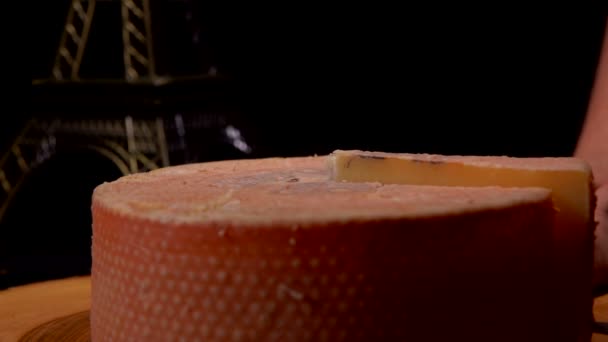 Mão tira um pedaço de queijo duro da roda de queijo de uma tábua de madeira — Vídeo de Stock