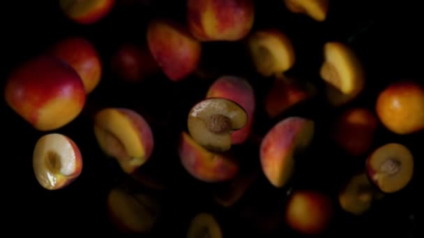 Metades de um pêssego maduro estão voando e girando em salpicos de suco — Vídeo de Stock