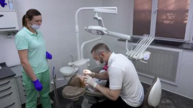 Diş hekimi küçük tatlı kıza diş muayenesi yapıyor. 