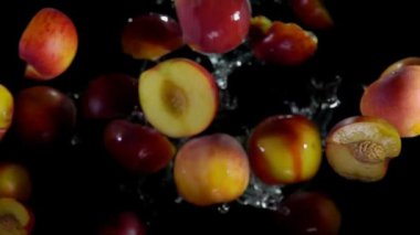 Taze şeftalinin yarısı, siyah bir arka planda su sıçramalarında zıplıyor.