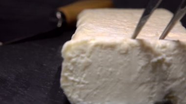 Özel bir bıçak bir parça keçi peynirini kara tahtaya koyar.
