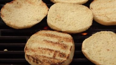 Izgarada susamlı hamburgerin yakın çekimi.